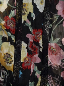 Detail of floral printed fabric with black lace stitching and pleated texture