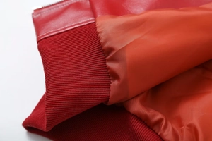 Detail shot of red PU leather texture, ribbed elastic cuff, and premium inner lining