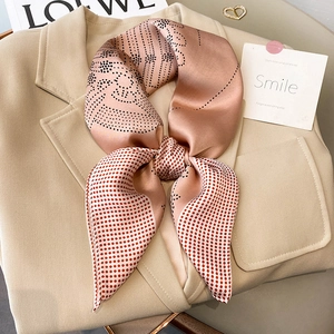 Pink silk scarf with red and black polka dots tied in a bow on a beige blazer