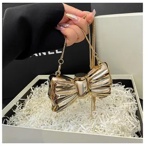 Detail of a shiny gold bow-shaped hardshell evening bag with elegant metal chain strap