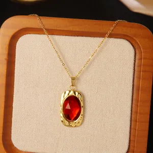 Detail of red oval gemstone pendant with hammered gold-tone wavy edges on linen display