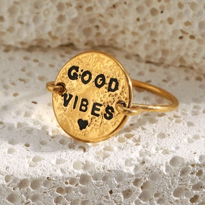 Macro detail of 18K gold plated ring with Good Vibes engraving on textured coin