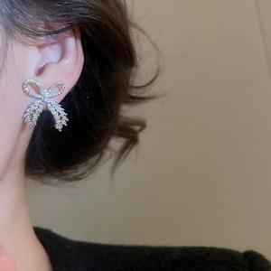 Close-up of sparkling zircon bow earring worn on model ear for an elegant look