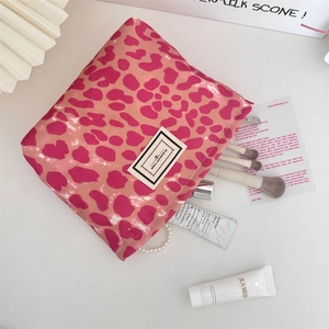 Vista piatta del beauty case leopardato rosa con pennelli e prodotti per la pelle