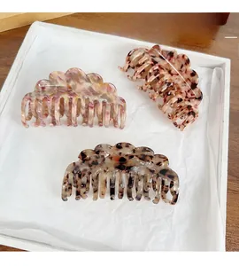 Detail of three acetate hair claws in pink marble, leopard print and tortoiseshell patterns