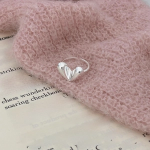 Elegant silver S925 heart ring on a pink sweater background with artistic aesthetic vibes