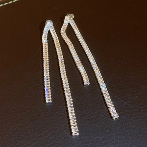 Dettaglio di orecchini pendenti vintage dorati con cristalli rettangolari brillanti