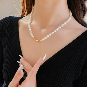 Close-up of minimalist pearl necklace with golden spherical magnetic clasp on collarbone