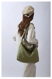 Dettaglio di una grande borsa a tracolla in tela verde indossata per un look casual unico