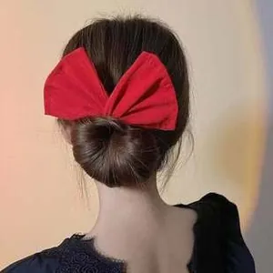 Detail of a large red bow hair accessory on a girl's bun hair styling tool