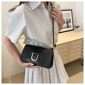 Détail du sac noir à texture crocodile avec boucle en U dorée et fine bandoulière
