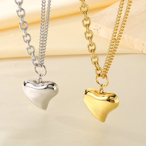 Detail of silver and gold puffed heart pendant necklaces with dual link chain design