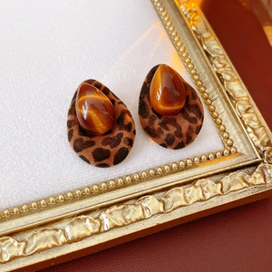 Detailed close-up of leopard print teardrop earrings with amber stones on gold frame