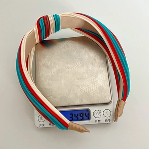 Close-up of a tricolor knotted headband showing weight on a digital scale for detail
