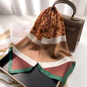 Elegante bufanda de seda con motivos geométricos en H sobre un bolso de piel marrón