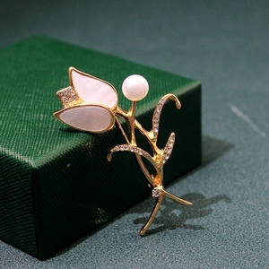 Detailed view of elegant gold tulip brooch with white pearl and sparkling crystals