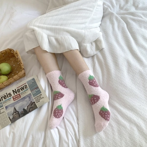 Detail of soft pink fuzzy socks with strawberry patterns shown in a cozy home setting