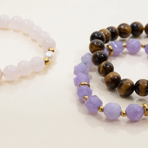 Macro shot of tiger eye, rose quartz and crystal beaded bracelets set with gold beads