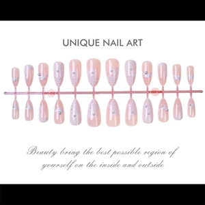 Detail of pink stiletto press-on nails with white floral designs and pearl accents