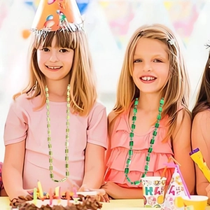 Close-up of kids wearing purple and green bead necklaces at a colorful birthday party