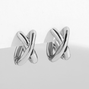 Detailed macro view of silver crossover X-shaped earrings with polished metallic finish