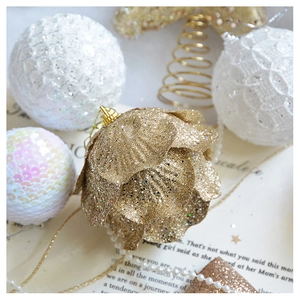 Close-up of champagne gold glitter flower ornaments and white textured Christmas bulbs
