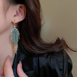 Detail of long gold tassel earrings with gradient blue and green rhinestones on model