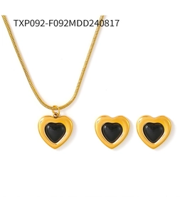 Detail of gold heart necklace and stud earrings set with black enamel and snake chain