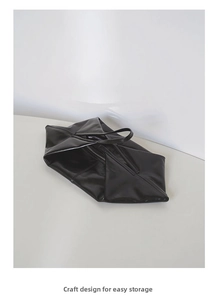Detail of a foldable black oil wax leather tote bag with a zipper and glossy texture