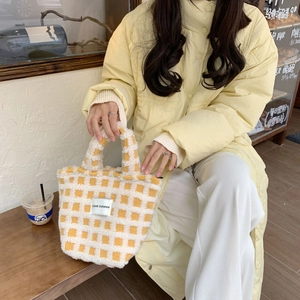 Detail of waffle lamb wool tote bag with yellow checkerboard pattern and logo patch