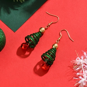 Detail of Christmas tree earrings with green glitter spiral and red bells on red background