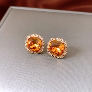 Détail de boucles d'oreilles ambrées avec halo de diamants et placage en or 18k