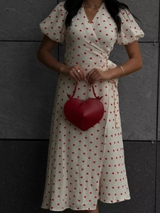 Detail of red heart-shaped handbag paired with white puff sleeve heart print dress