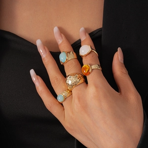 Detail of 5-piece vintage gold metal ring set with colorful resin oval gemstones