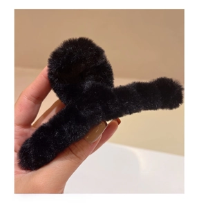 Gros plan d'une pince à cheveux noire en peluche douce avec texture en fausse fourrure