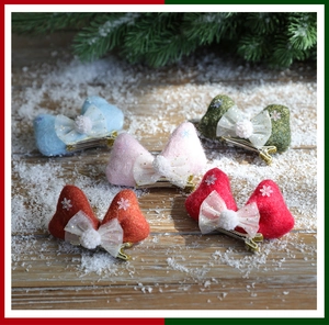 Detailed view of colorful plush Christmas bow hair clips with snowflakes on a wooden surface