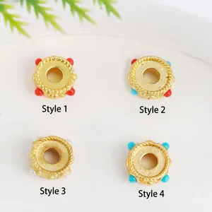 Detail of four gold-plated spacer beads with twisted texture and colorful enamel stones
