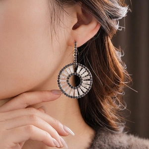 Elegant gold-tone circular earrings with radiant blue and clear crystals on model