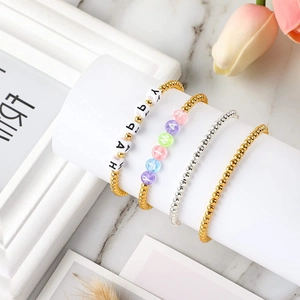 Set of gold and silver beaded bracelets with HAPPY and FAMILY letter charms on a display stand