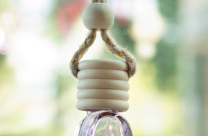 Macro detail of wooden cap and glass bottle for 6ml car perfume with violet liquid