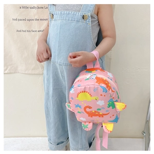 Pink cartoon dinosaur toddler backpack being held by child model in a playful setting