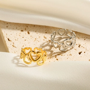 Detailed view of gold and silver cutout heart rings on a textured stone and silk surface