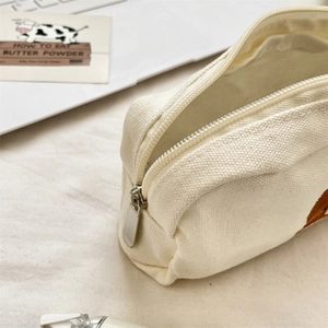 Close-up of cream canvas pencil case showing durable metal zipper and soft fabric texture
