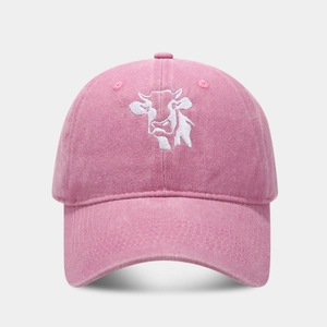 Close-up of pink washed cotton baseball cap featuring detailed white cow embroidery