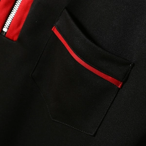 Detail of black pique polo shirt featuring a red accent line and silver metal zipper pocket