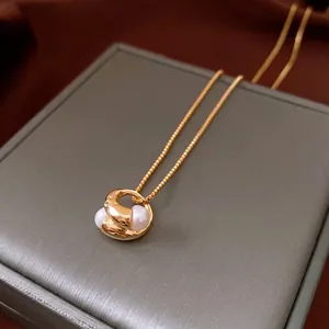 Elegant 18k gold plated necklace with twisted ring and double pearls on a jewelry box