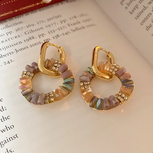 Baroque style gold U-shape earrings with purple zircon beads on vintage book pages