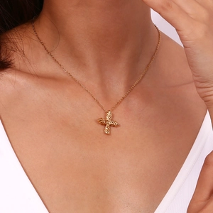 Macro detail of 18K gold plated cross necklace with hammered lava texture