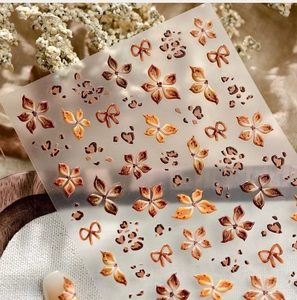 Makroaufnahme von 5D geprägten Nagelstickern mit Herbstblumen und Leopardenmustern