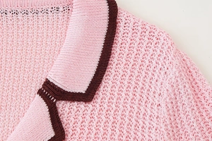Close-up of pink knit cardigan with chocolate contrast trim and fine hollow texture